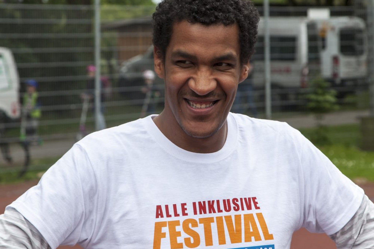 Lächelnder junger Mann mit T-Shirt-Aufdruck: Alle Inklusive Festival