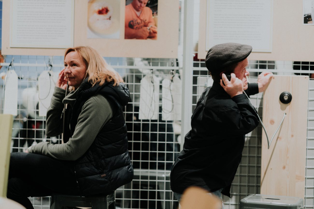 Zwei Menschen hören akustische Infos einer Ausstellung ab.